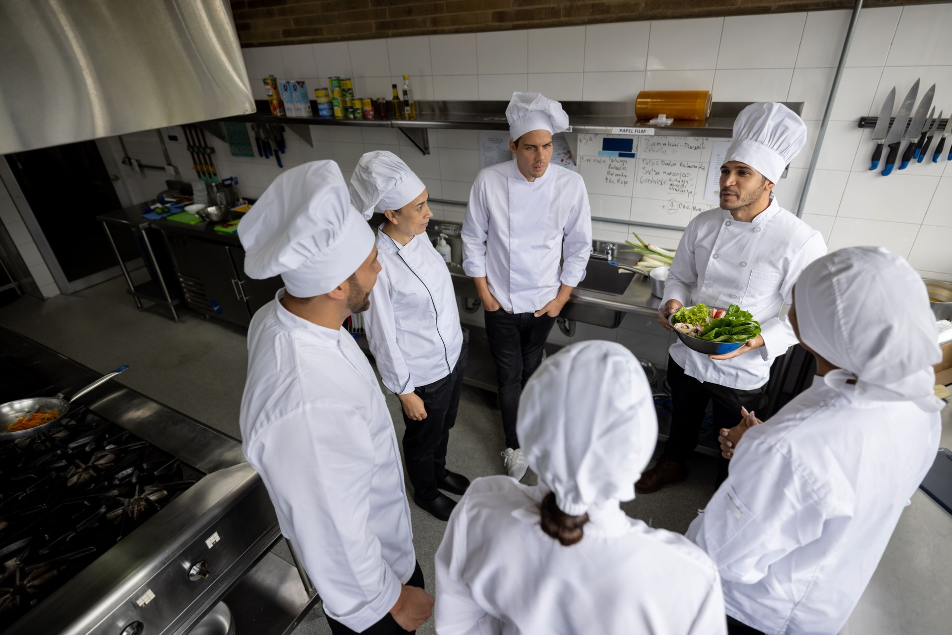 Head chef talking to a group of cooks in the kitchen of a restaurant